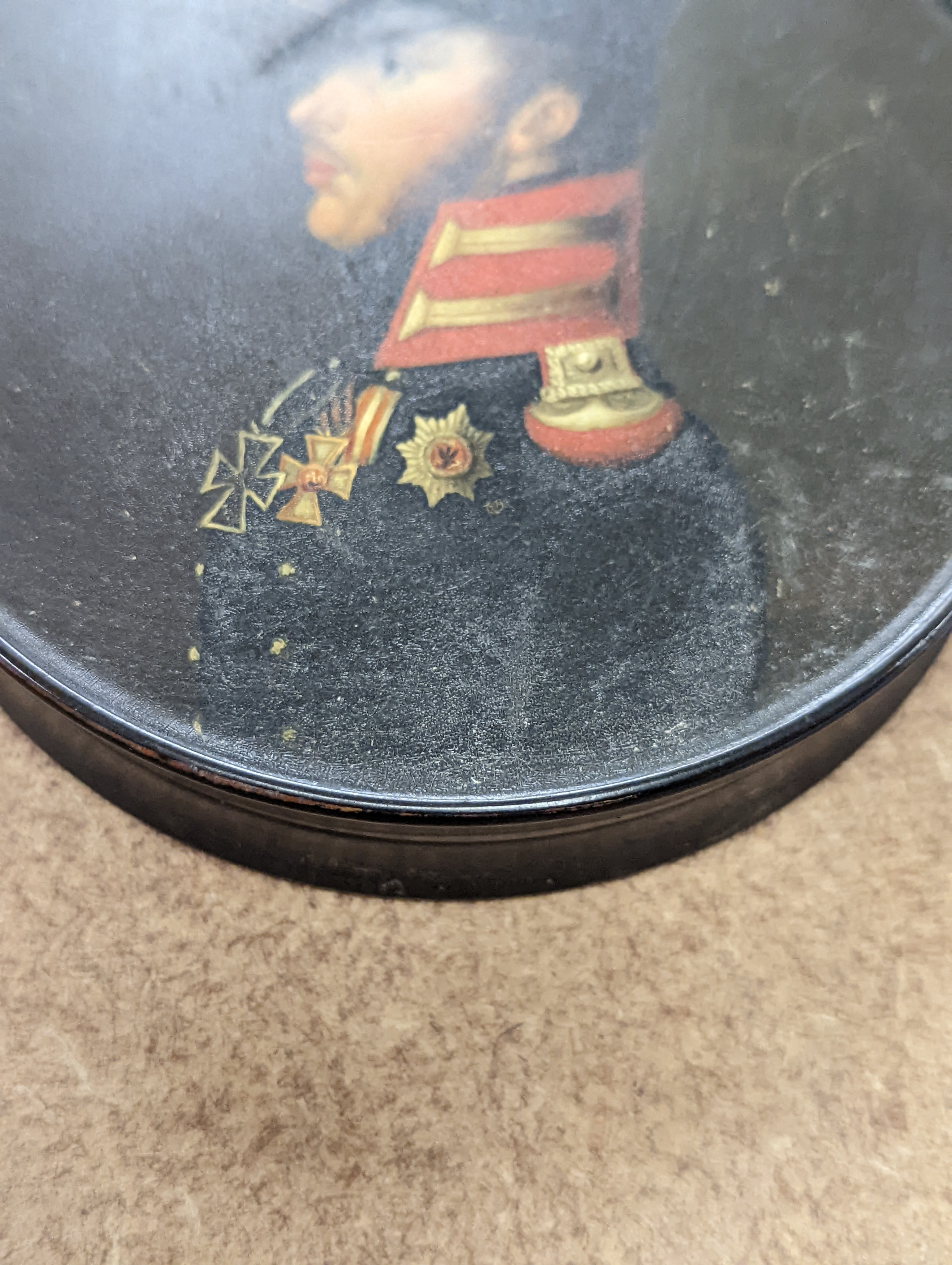 A 19th century Stobwasser papier mache ‘Henriette Sonntag’ portrait snuff box, c.1830, 9.7cm diameter and a 19th-century papier mache snuff box painted with a portrait of a German hussar, 9.4cm (2)